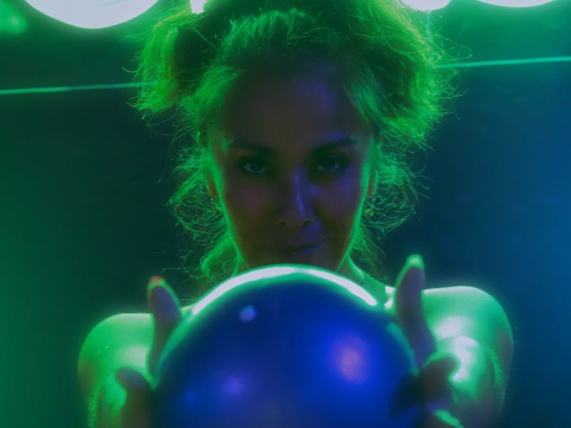 Person performing dynamic exercises in a neon lit studio